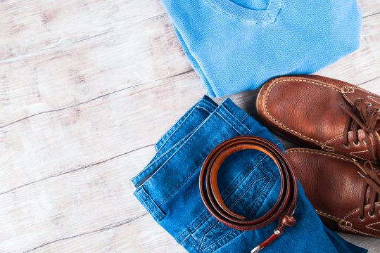 Man's clothes flat lay with blue jeans, T-shirt, pullover, leather shoes and belt